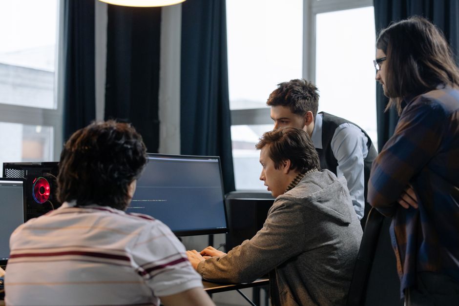 Group of developers working together on a computer programming project indoors.